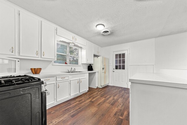 2801 John St, La Marque, TX 77568 - kitchen featuring white refrigerator with ice dispenser, dark wood-style flooring, white cabinetry, light countertops, and black gas range