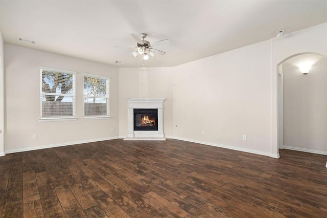 24727 Lake Basin Ct, Katy, TX 77493 - unfurnished living room featuring ceiling fan, dark wood-style flooring, arched walkways, and a glass covered fireplace