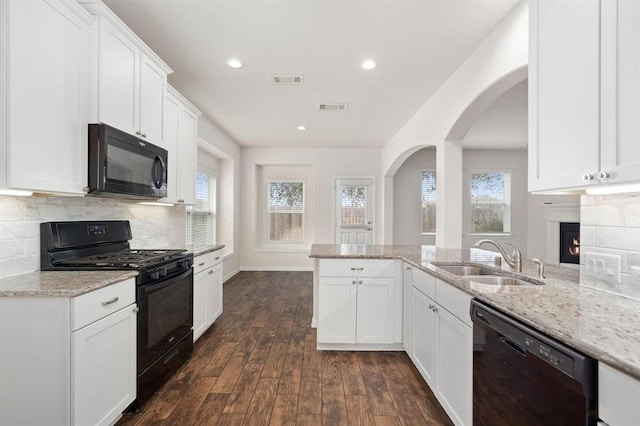 24727 Lake Basin Ct, Katy, TX 77493 - kitchen with black appliances, light stone counters, dark wood-style floors, backsplash, and recessed lighting