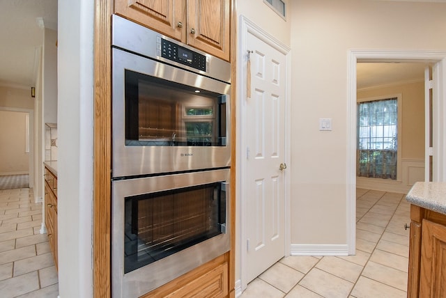 3003 Bernadette Ln, Houston, TX 77043 - kitchen with double oven, ornamental molding, light tile patterned floors, and light stone countertops