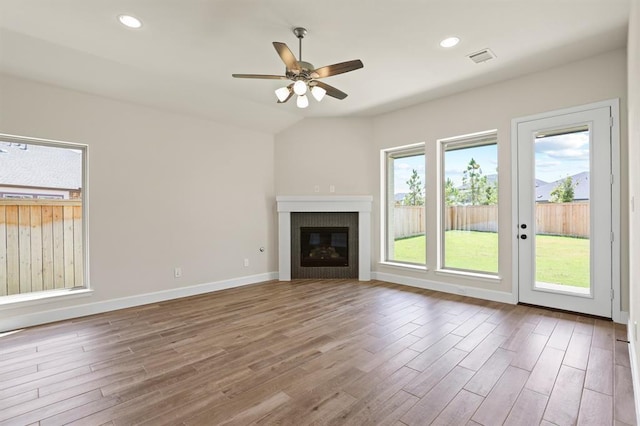 18511 Wolf Mountain Ln, Cypress, TX 77433 - unfurnished living room featuring wood finished floors, a ceiling fan, a glass covered fireplace, recessed lighting, and lofted ceiling