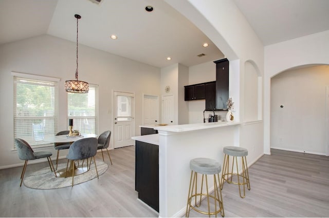 17603 Memorial Falls Dr, Tomball, TX 77375 - kitchen featuring arched walkways, light wood-type flooring, light countertops, vaulted ceiling, and recessed lighting