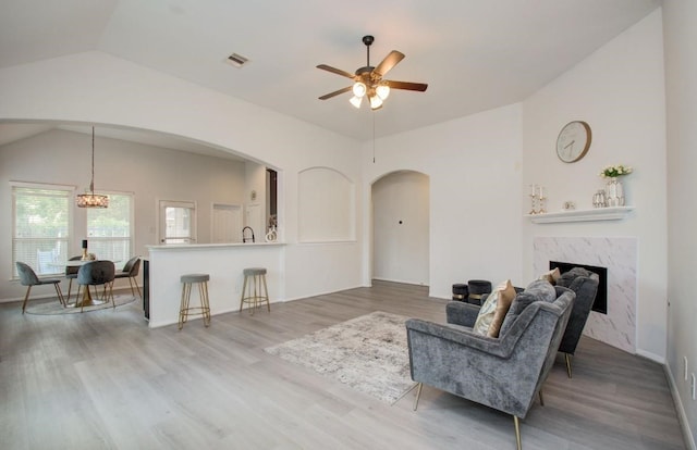 17603 Memorial Falls Dr, Tomball, TX 77375 - living area with arched walkways, vaulted ceiling, ceiling fan, wood finished floors, and a premium fireplace
