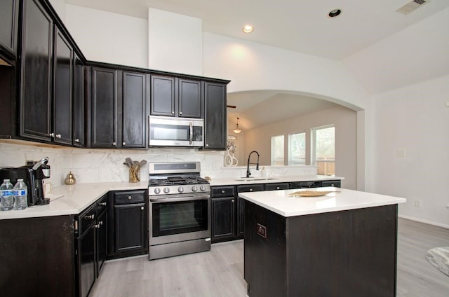 17603 Memorial Falls Dr, Tomball, TX 77375 - kitchen featuring stainless steel appliances, lofted ceiling, arched walkways, light wood-style floors, and tasteful backsplash