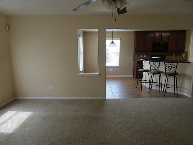22303 Bridgestone Ridge Dr, Spring, TX 77388 - kitchen with black microwave, ceiling fan, a breakfast bar, light carpet, and pendant lighting
