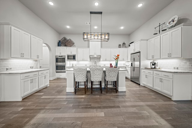 30 Madrone Terrace Pl, Tomball, TX 77375 - kitchen featuring stainless steel appliances, decorative backsplash, white cabinetry, a breakfast bar area, and recessed lighting