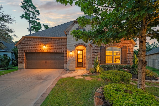 30 Madrone Terrace Pl, Tomball, TX 77375 - french country inspired facade with brick siding, an attached garage, concrete driveway, and roof with shingles