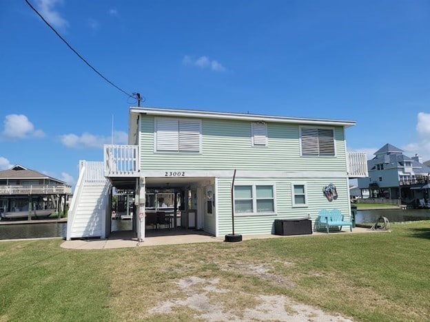 23002 Vida, Galveston, TX 77554 - rear view of house featuring a yard, stairs, a patio, and a carport