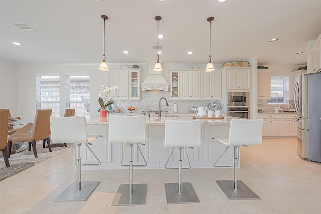 47 Monarch Trl, Sugar Land, TX 77498 - kitchen with stainless steel appliances, decorative backsplash, a center island with sink, a kitchen bar, and glass insert cabinets