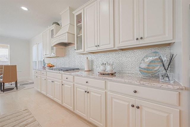 47 Monarch Trl, Sugar Land, TX 77498 - kitchen featuring stainless steel gas stovetop, decorative backsplash, glass insert cabinets, light stone countertops, and recessed lighting