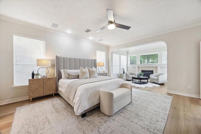 12410 Sonata Canyon Ln, Houston, TX 77041 - bedroom featuring ornamental molding, a glass covered fireplace, light wood-style flooring, and a ceiling fan