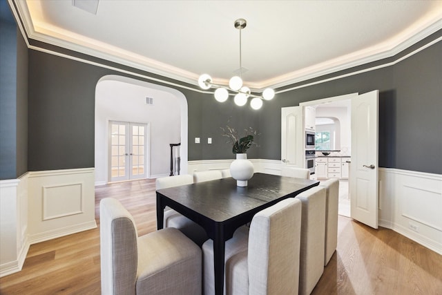 12410 Sonata Canyon Ln, Houston, TX 77041 - dining room featuring arched walkways, a raised ceiling, a wainscoted wall, light wood finished floors, and a decorative wall