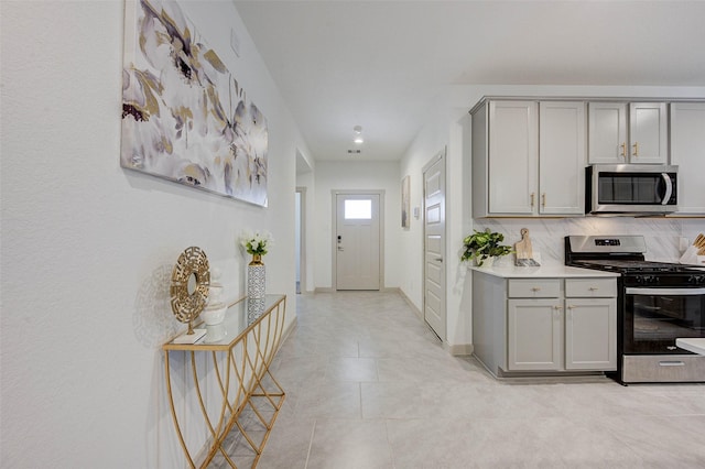 29918 Reagans Ranch Dr, Katy, TX 77494 - kitchen with stainless steel appliances, gray cabinetry, light countertops, light tile patterned floors, and tasteful backsplash