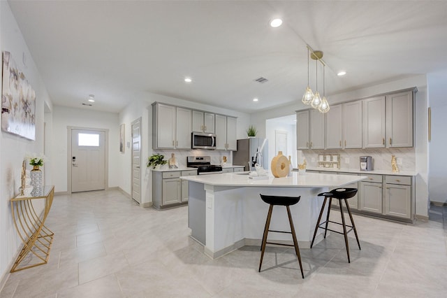 29918 Reagans Ranch Dr, Katy, TX 77494 - kitchen featuring stainless steel appliances, gray cabinetry, backsplash, a breakfast bar, and light countertops