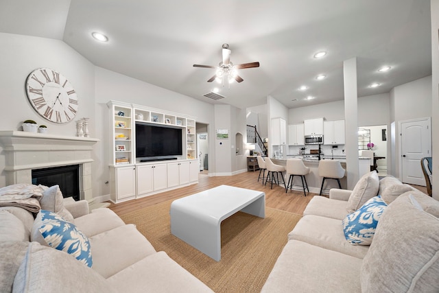 2707 Wollemi Pine Trl, Katy, TX 77493 - living room featuring ceiling fan, light wood finished floors, a glass covered fireplace, recessed lighting, and stairway