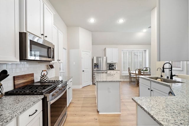 2707 Wollemi Pine Trl, Katy, TX 77493 - kitchen with stainless steel appliances, light wood finished floors, white cabinets, light stone counters, and recessed lighting