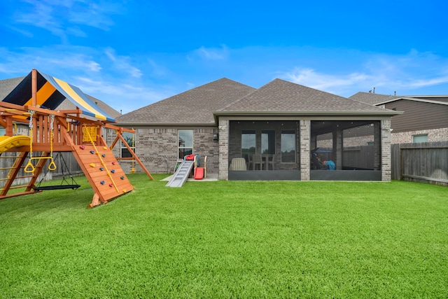 2707 Wollemi Pine Trl, Katy, TX 77493 - back of house featuring a playground, a shingled roof, brick siding, and a sunroom