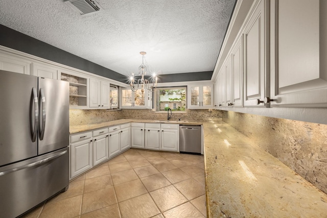 5610 Edgewick Ct, Houston, TX 77069 - kitchen with appliances with stainless steel finishes, a chandelier, white cabinetry, decorative light fixtures, and a textured ceiling