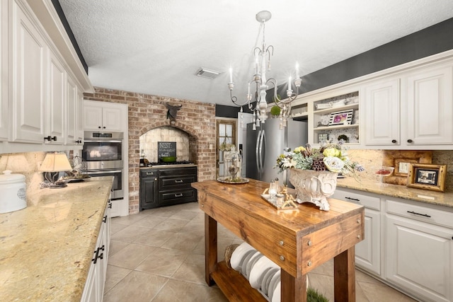 5610 Edgewick Ct, Houston, TX 77069 - kitchen with appliances with stainless steel finishes, white cabinetry, light tile patterned floors, a chandelier, and a textured ceiling