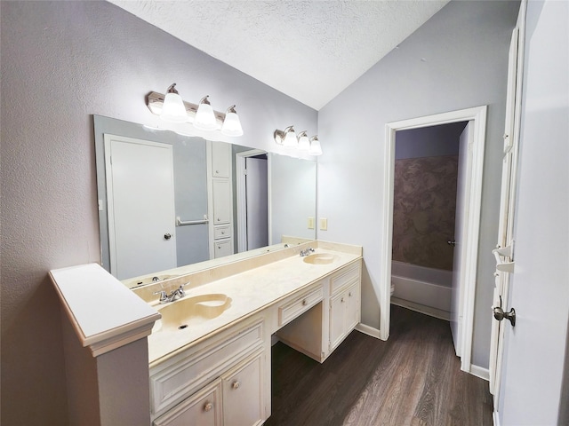 15006 Yorktown Colony Dr, Houston, TX 77084 - bathroom featuring vaulted ceiling, double vanity, wood finished floors, and a textured ceiling