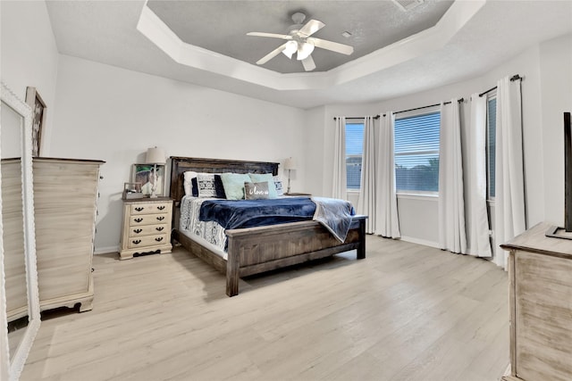 9826 Palm Dr, Mont Belvieu, TX 77523 - bedroom with a raised ceiling, light wood-style flooring, and ceiling fan