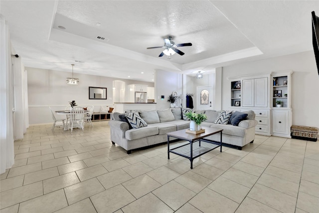 9826 Palm Dr, Mont Belvieu, TX 77523 - living room featuring a tray ceiling, a ceiling fan, light tile patterned floors, and a textured ceiling
