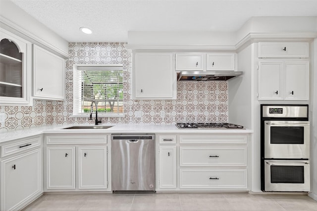 19502 Enchanted Oaks Dr, Spring, TX 77388 - kitchen featuring stainless steel appliances, under cabinet range hood, white cabinets, light countertops, and backsplash