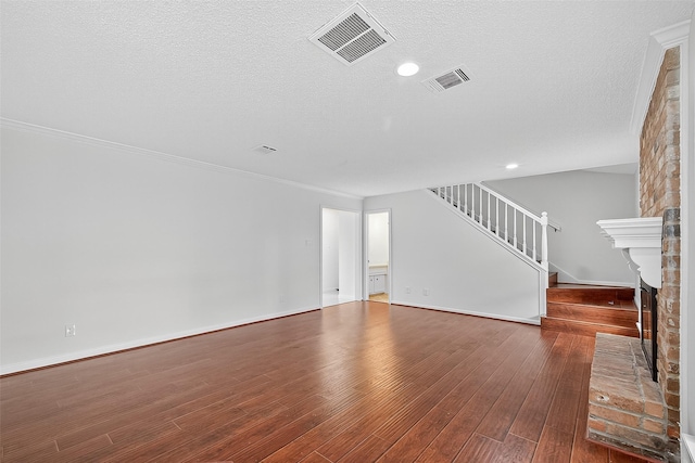 19502 Enchanted Oaks Dr, Spring, TX 77388 - unfurnished living room with stairs, hardwood / wood-style floors, a fireplace, a textured ceiling, and crown molding