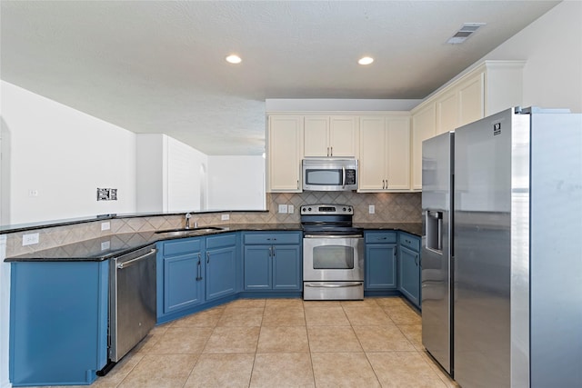 23307 W Pine Ivy Ln, Tomball, TX 77375 - kitchen with stainless steel appliances, blue cabinetry, a peninsula, decorative backsplash, and light tile patterned floors