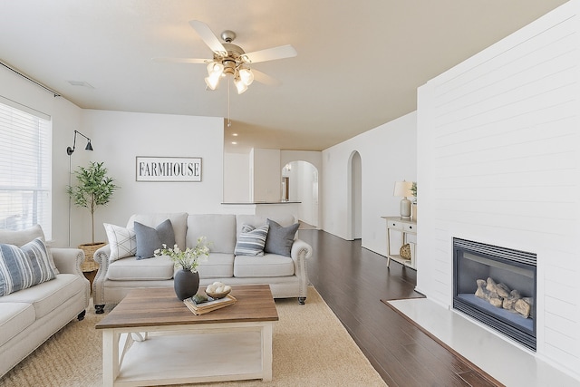 23307 W Pine Ivy Ln, Tomball, TX 77375 - living area with arched walkways, a ceiling fan, wood finished floors, and a glass covered fireplace