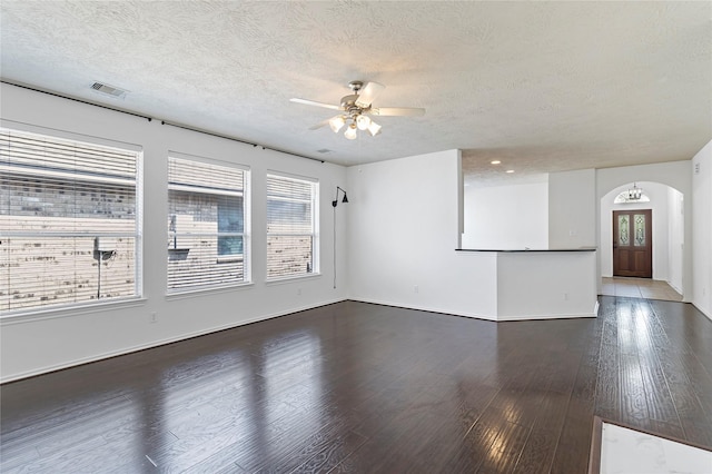 23307 W Pine Ivy Ln, Tomball, TX 77375 - unfurnished living room with arched walkways, a ceiling fan, plenty of natural light, a textured ceiling, and dark wood-style flooring