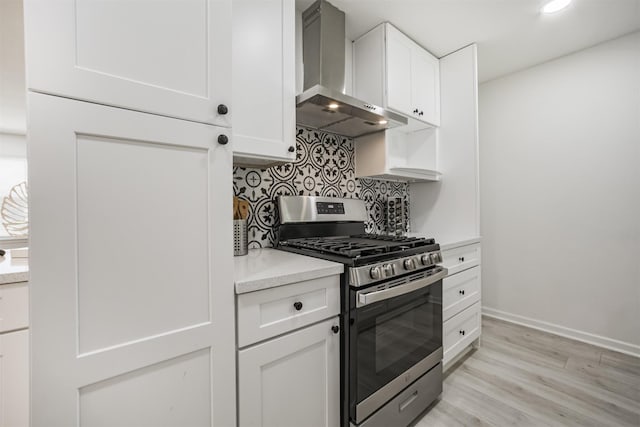 4330 Heite St, Houston, TX 77022 - kitchen featuring gas stove, wall chimney range hood, tasteful backsplash, light wood-style floors, and white cabinetry