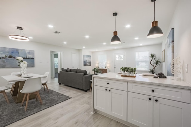 4330 Heite St, Houston, TX 77022 - kitchen featuring pendant lighting, white cabinets, light wood-type flooring, a peninsula, and recessed lighting