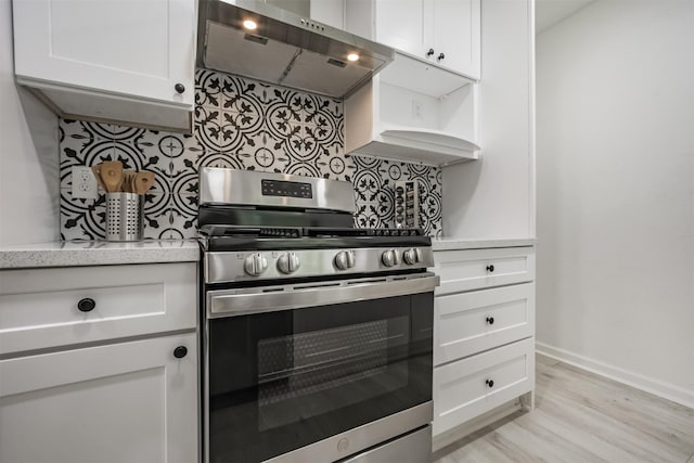 4330 Heite St, Houston, TX 77022 - kitchen featuring stainless steel range with gas cooktop, exhaust hood, decorative backsplash, white cabinets, and light wood-type flooring