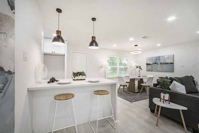 4330 Heite St, Houston, TX 77022 - kitchen with white cabinetry, light wood-style flooring, pendant lighting, a peninsula, and a breakfast bar area