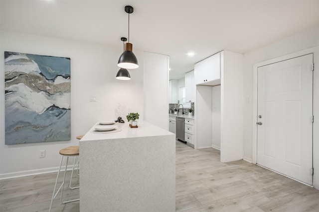 4330 Heite St, Houston, TX 77022 - kitchen featuring dishwasher, light wood finished floors, white cabinets, light countertops, and pendant lighting