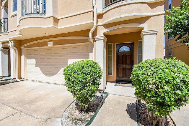 5615 Winsome Ln Unit C, Houston, TX 77057 - view of exterior entry with an attached garage, stucco siding, a balcony, and concrete driveway