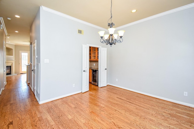 5615 Winsome Ln Unit C, Houston, TX 77057 - empty room with beverage cooler, ornamental molding, light wood-style flooring, a chandelier, and recessed lighting