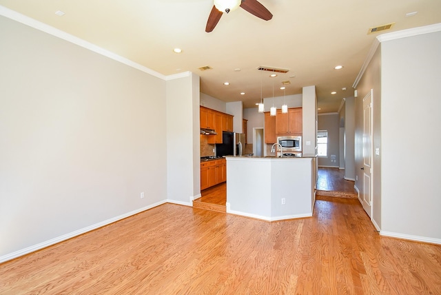 5615 Winsome Ln Unit C, Houston, TX 77057 - kitchen with stainless steel microwave, ornamental molding, black fridge with ice dispenser, light wood-type flooring, and brown cabinetry