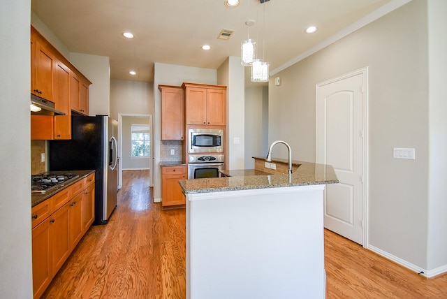 5615 Winsome Ln Unit C, Houston, TX 77057 - kitchen featuring stainless steel appliances, under cabinet range hood, backsplash, light wood-style flooring, and a kitchen island with sink
