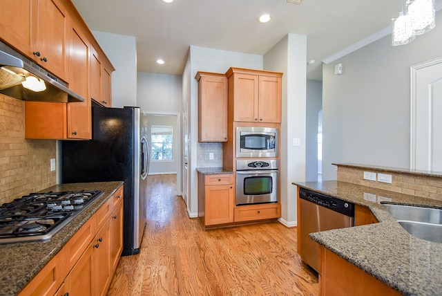 5615 Winsome Ln Unit C, Houston, TX 77057 - kitchen featuring stainless steel appliances, under cabinet range hood, light wood-type flooring, tasteful backsplash, and dark stone counters