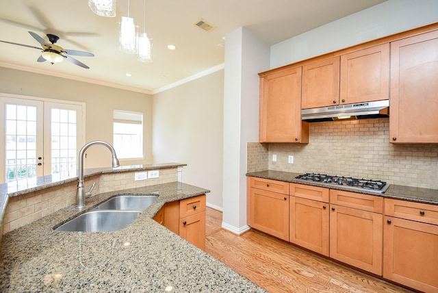 5615 Winsome Ln Unit C, Houston, TX 77057 - kitchen with stainless steel gas stovetop, under cabinet range hood, light wood-type flooring, ceiling fan, and backsplash