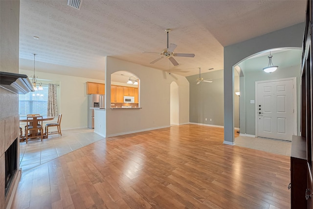 30606 S Sulphur Creek Dr, Magnolia, TX 77355 - unfurnished living room with arched walkways, a ceiling fan, light wood-style flooring, and a textured ceiling