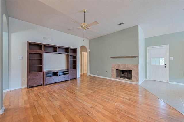 30606 S Sulphur Creek Dr, Magnolia, TX 77355 - unfurnished living room featuring arched walkways, a ceiling fan, wood finished floors, and a tile fireplace