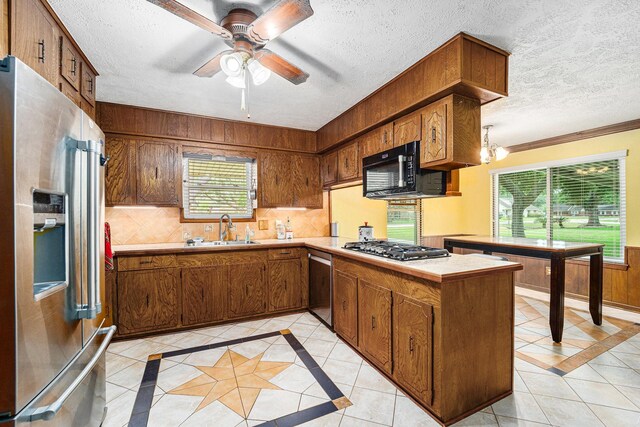 2505 Mary Ave, Pearland, TX 77581 - kitchen featuring stainless steel appliances, inlaid floor details, a textured ceiling, light countertops, and brown cabinetry