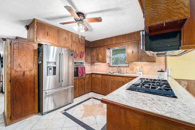 2505 Mary Ave, Pearland, TX 77581 - kitchen with black appliances, light tile patterned floors, brown cabinetry, light countertops, and a textured ceiling