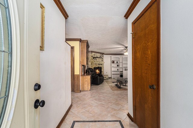 2505 Mary Ave, Pearland, TX 77581 - foyer entrance with a textured ceiling, a brick fireplace, ornamental molding, ceiling fan, and light tile patterned flooring