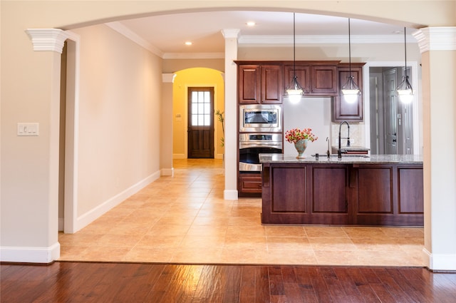 2715 Joshua Tree Ln, Manvel, TX 77578 - kitchen with appliances with stainless steel finishes, arched walkways, light stone counters, light wood-style floors, and crown molding