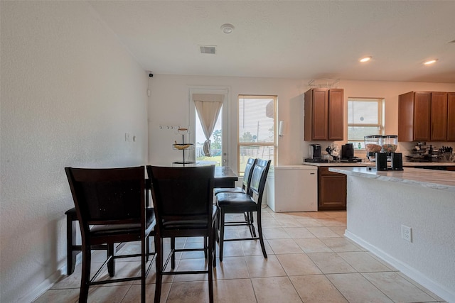 602 Willow Briar Dr, Houston, TX 77090 - kitchen featuring healthy amount of natural light, refrigerator, brown cabinets, light tile patterned floors, and recessed lighting