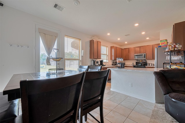 602 Willow Briar Dr, Houston, TX 77090 - kitchen with stainless steel microwave, gas stove, freestanding refrigerator, light countertops, and light tile patterned flooring